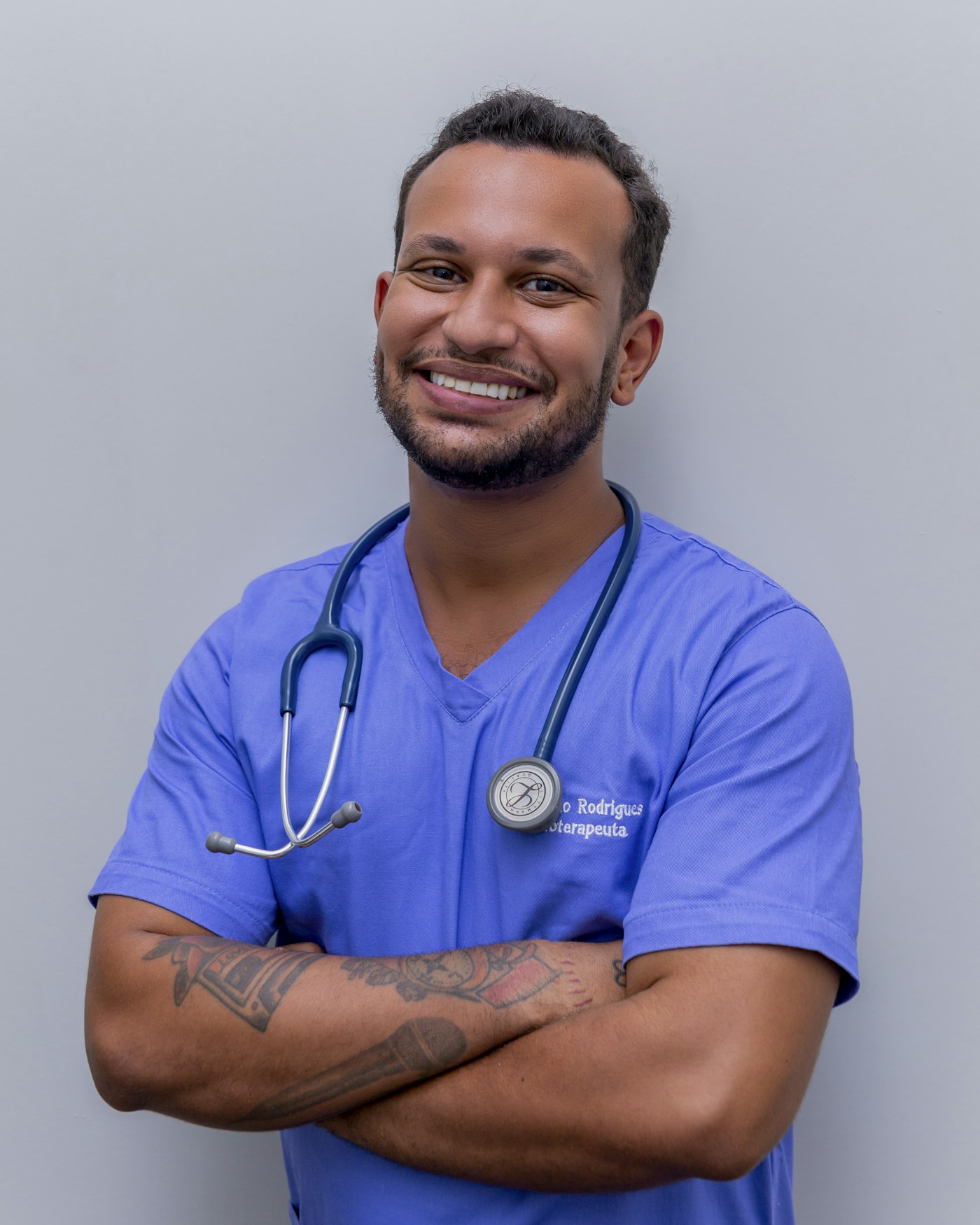 Profissional de saúde sorrindo, com uniforme azul e estetoscópio